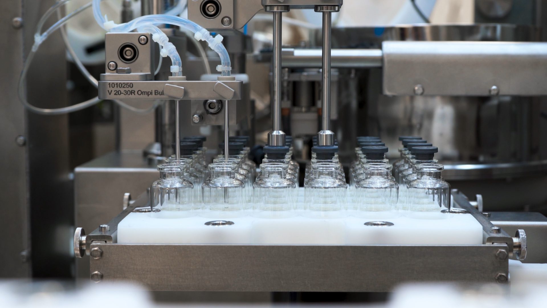 Glass vials moving through an automated sterile filling and stoppering line