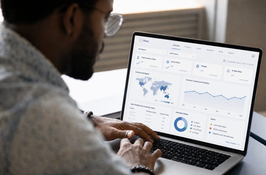 A man reviewing a Sharp inventory dashboard on a laptop, showing stock levels by region, inventory trends and supply alerts